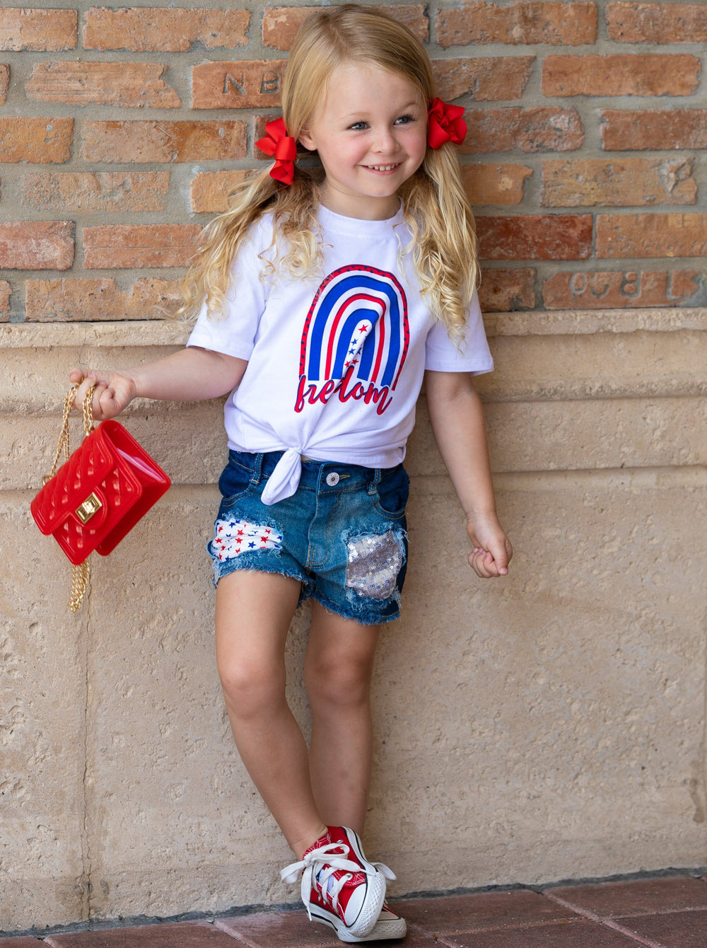 Girls set features a white top with "Freedom" print and patched denim shorts with a red sash