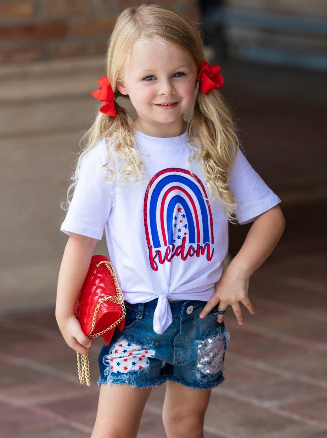 Girls set features a white top with "Freedom" print and patched denim shorts with a red sash